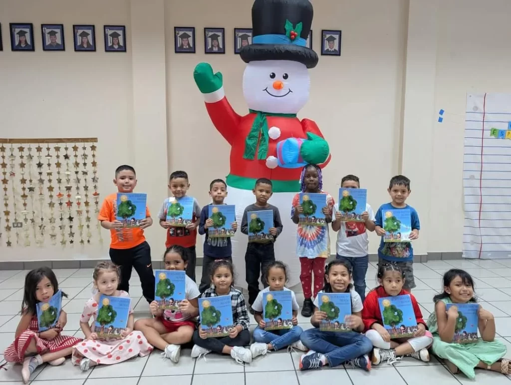 Group of children pose together indoors with an oversized snowman figure.